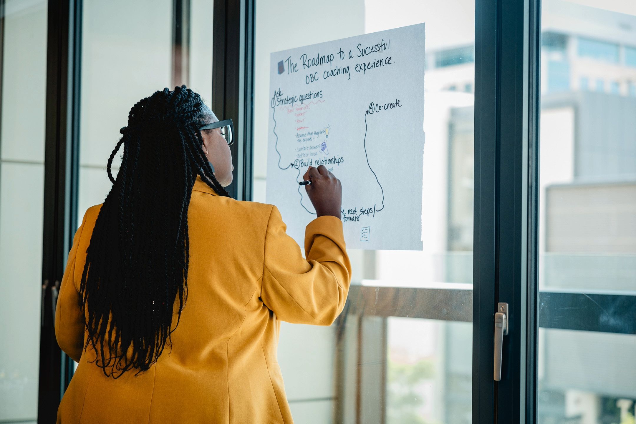 A woman writes on a piece of paper about effective OBC leadership coaching